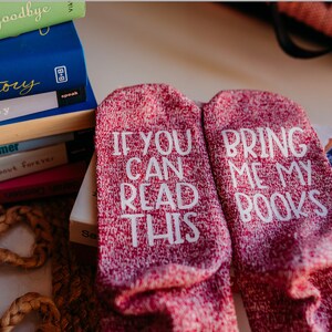 Pode incluir: Um par de meias vermelhas e brancas com o texto "Se você pode ler isso, traga meus livros" nelas.