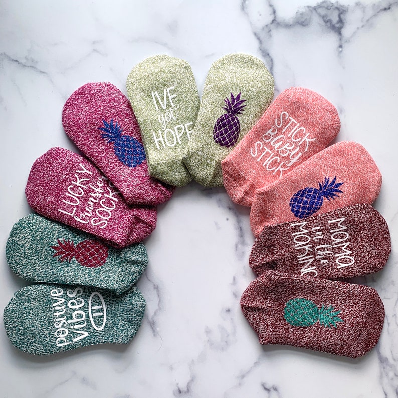 May include: A set of ten colorful ankle socks with pineapple designs and various phrases, including "Lucky Transfer Sock", "Positive Vibes", "Ive got Hope", "Stick Baby Stick", "Mama in the Morning".