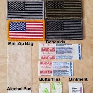 May include: A first aid kit with a variety of items, including bandages, alcohol prep pads, ointment, and butterflies. The kit also includes a mini zip bag and several American flag patches.