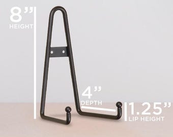 May include: A black metal display stand with a triangular frame and two front-facing hooks. The stand features an 8-inch height, a 4-inch depth, and a 1.25-inch lip height, as indicated by the white measurement text and lines overlaid on the image.