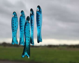 fish wind chimes hanging from driftwood. Fishes made in fused glass and make a lovely wind chime.