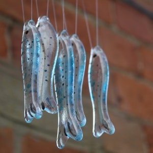 fish wind chimes hanging from driftwood. Fishes made in fused glass and make a lovely wind chime. clear and blue