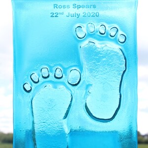 Puede incluir: Una placa de vidrio azul claro con la inscripci&oacute;n "Ross Spears 22nd July 2020" y dos huellas de manos claras.