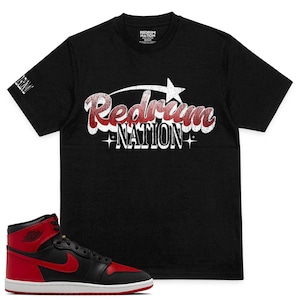Könnte beinhalten: Schwarzes T-Shirt mit einem weißen "Redrum Nation"-Motiv im Retro-Stil. Ein roter und schwarzer Air Jordan 1 Sneaker ist ebenfalls abgebildet.