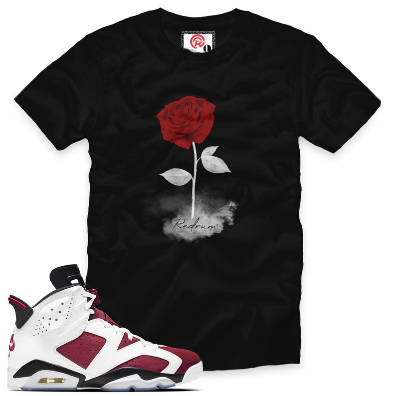 May include: Black t-shirt with a white rose and the word "Redrum" printed on it.  A pair of white and burgundy Air Jordan 6 Retro sneakers.