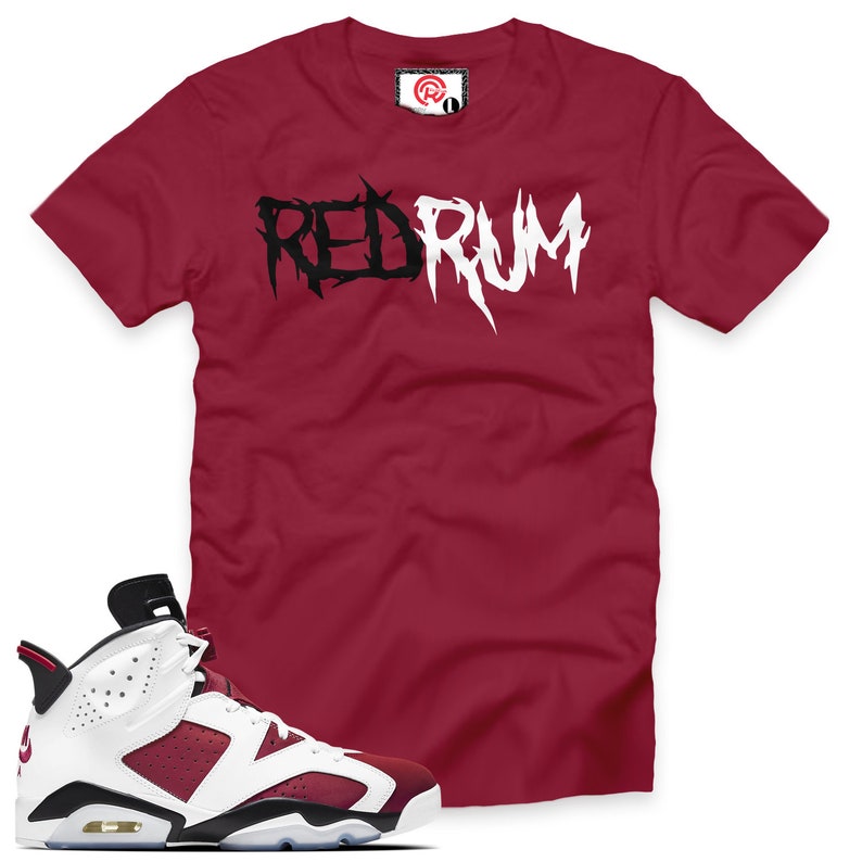 May include: A red t-shirt with the word "REDRUM" printed in black and white letters. A pair of white and burgundy sneakers with black accents.