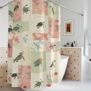 以下が含まれることがあります： カメ、花、植物の要素が緑、ピンク、クリーム色で描かれたパッチワークデザインのシャワーカーテン。カーテンはバスルームに吊るされています。
