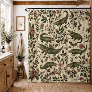 May include: A shower curtain featuring a repeating pattern of green alligators interspersed with dark red floral motifs and green leafy vines on a cream-colored background with subtle vertical stripes throughout the fabric design.
