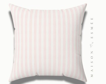 May include: A pink and white striped throw pillow with the text "MAISON ESMÉE" in a white font on the right side.