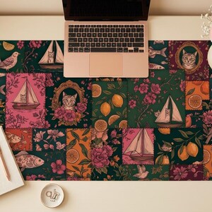 Puede incluir: Alfombrilla de escritorio decorativa con un diseño de patchwork con veleros, gatos, limones y flores. Una computadora portátil, un cuaderno y un lápiz están sobre la alfombrilla.