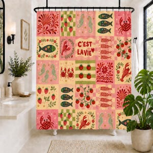 May include: A shower curtain featuring a patchwork grid of illustrations including red crabs, green seahorses, patterned fish, strawberries, and tomato vines. The center square displays the red text C'EST LAVIE with a small red heart icon.