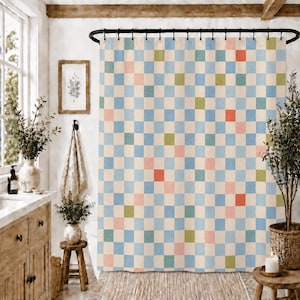 May include: A shower curtain featuring a grid pattern of small squares in light blue, cream, soft pink, muted green, and coral orange. The curtain hangs from a black metal rod with rings and covers the width of the wall in a bathroom setting.