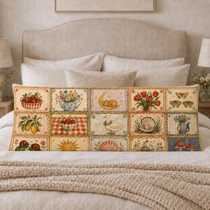 Puede incluir: Un cojín lumbar rectangular largo que presenta una cuadrícula de doce paneles ilustrados. Los diseños incluyen una cesta de fresas, una tetera con flores, un gato en una luna creciente, tulipanes rojos, mariposas, limones, cerezas, un ganso, una perla en una concha, un sol y setas.