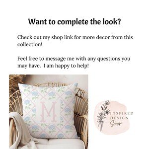 May include: A pink and blue patterned throw pillow with a white letter M in the center. The pillow is sitting on a wicker chair. The image also includes a logo for Inspired Design Shoppe.