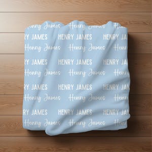 May include: A light blue baby blanket with the name "Henry James" repeated in white text.