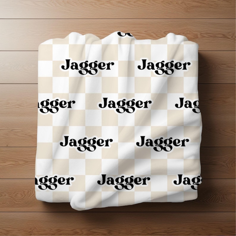 K&ouml;nnte beinhalten: Wei&szlig;er und beiger karierter Stoff mit dem Wort "Jagger" in schwarzer Retro-Schrift wiederholt.