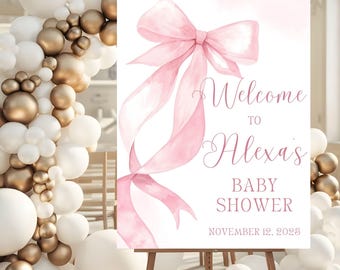 May include: A rectangular welcome sign for a baby shower featuring a large watercolor pink ribbon illustration. The text reads Welcome to Alexa's BABY SHOWER NOVEMBER 12, 2025 in pink lettering on a white background.
