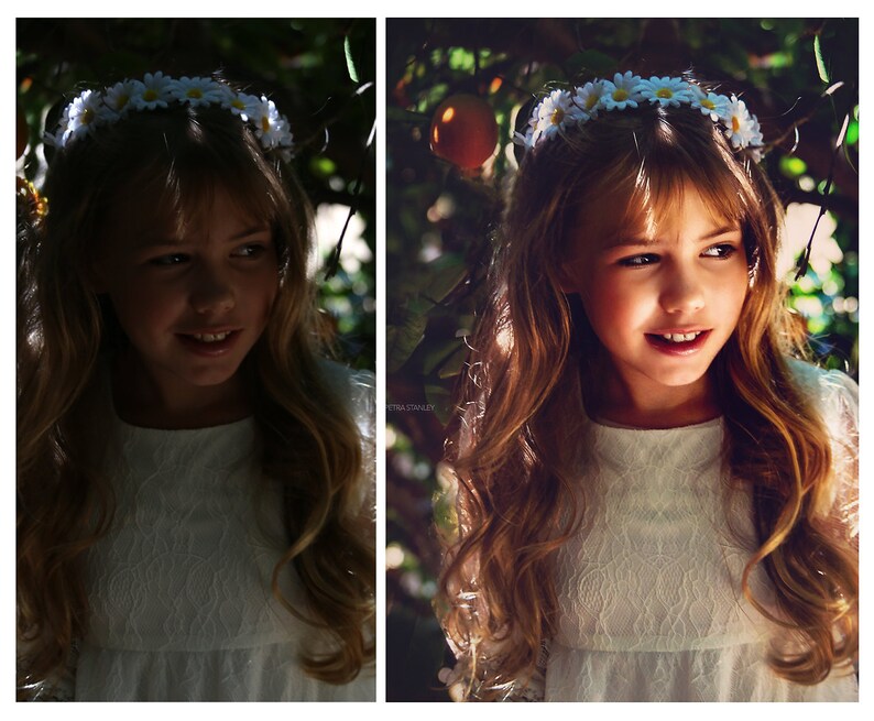 May include: A young girl with long brown hair wears a white dress and a flower crown. She is smiling and looking to the side. The background is a blurred image of green leaves and a bright orange fruit.
