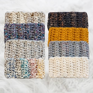May include: A stack of six crocheted headbands in various colors and patterns, including white, gray, brown, blue, and yellow.