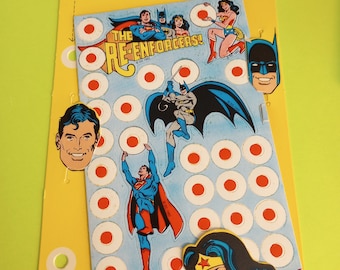 Pode incluir: Um cartão amarelo e azul com uma imagem do Superman, Mulher Maravilha e Batman. O cartão diz "Super Heroes School Stickers" e "The Re-Enforcers!" com um círculo vermelho ao redor do texto. O cartão também tem 5 folhas de adesivos com círculos vermelhos.