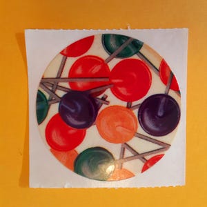 May include: A circular sticker with a colorful design. It features red, green, orange, and purple circles connected by thin gray lines. The sticker is on a white square, set against a yellow background.