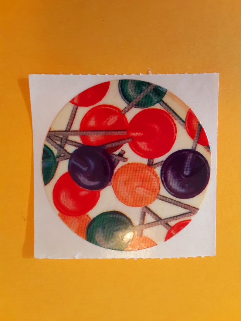May include: A circular sticker with a colorful design. It features red, green, orange, and purple circles connected by thin gray lines. The sticker is on a white square, set against a yellow background.