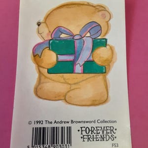 May include: A Forever Friends sticker featuring a tan teddy bear holding a teal gift box tied with a blue ribbon. The sticker has the text "Forever Friends" and the copyright information for The Andrew Brownsword Collection.
