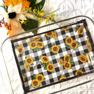 May include: A black and white checkered baking dish liner with a sunflower pattern. The liner is in a clear glass baking dish.