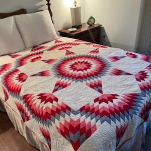 May include: A vintage quilt with a large, red, pink, and gray star pattern. The quilt is made of cotton fabric and is in good condition.