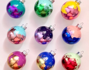 May include: Nine glass ornaments with a variety of colors and metallic accents. The ornaments are decorated with gold, silver, and copper paint splatters. The ornaments are perfect for adding a touch of sparkle to your Christmas tree.