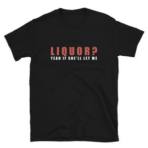 May include: A black short-sleeved t-shirt featuring the text LIQUOR? in large red letters on the top line, followed by the text YEAH IF SHE'LL LET ME in smaller white capital letters centered directly underneath on the chest area.