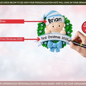 May include: A blue and white baby ornament with a wreath and a ribbon. The ornament says "Brian" and "First Christmas 2022".