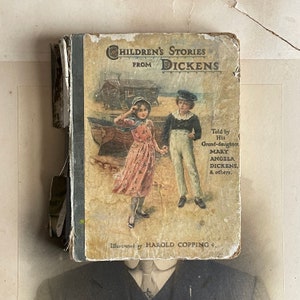 Puede incluir: Un libro infantil vintage titulado "Children's Stories from Dickens" con ilustraciones de dos niños en una playa. La portada del libro está amarillenta y desgastada por el paso del tiempo. El texto de la portada dice "Told by His Grand-daughter, Mary Angela Dickens, & others." y "Illustrated by Harold Copping."