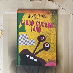 May include: A vibrant book cover for "Cloud Cuckoo Land". The design includes the text "Wavey Snots Presents" and the title in pink and yellow. The illustration features a cartoon monster with large eyes and a dotted cloud against a yellow background.