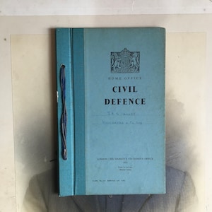 May include: A blue book titled "Civil Defence" with the text "Home Office" and "J.A.G. Harley" written on the cover. The book was published by His Majesty's Stationery Office in 1951.