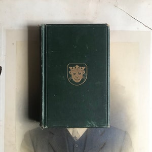 May include: A dark green hardback book with a gold lion head crest on the front cover.