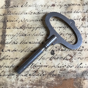 May include: A vintage metal key with a large, oval-shaped head and a long, thin shaft. The key has a number "4" stamped on the head.