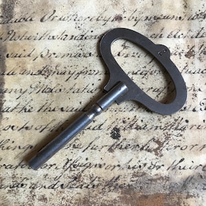 May include: A vintage metal key with a large, oval-shaped head and a long, thin shaft. The key is slightly tarnished and has a number "3" stamped on the head.