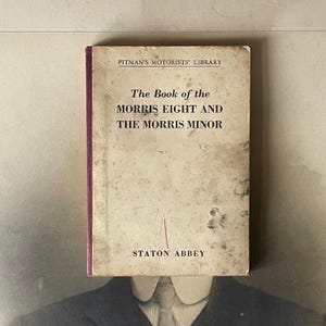 May include: A vintage book titled "The Book of the Morris Eight and The Morris Minor" by Staton Abbey. The book is part of Pitman's Motorists' Library series.