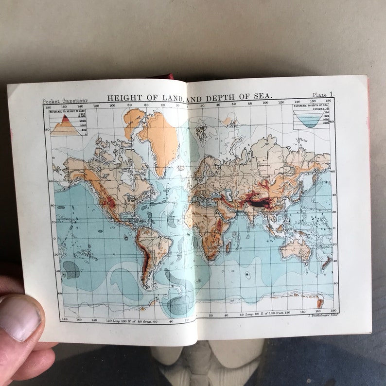 Op de afbeelding: Een vintage kaart die de hoogte van het land en de diepte van de zee laat zien. De kaart is gedrukt in blauw, bruin en rood op een witte achtergrond. De kaart heeft de titel "Hoogte van het land en diepte van de zee" en "Plaat 1."