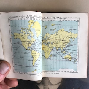 Op de afbeelding: Een vintage kaart die de belangrijkste handelsroutes over de hele wereld laat zien. De kaart is gedrukt op een lichtblauwe achtergrond met gele continenten en rode lijnen die de handelsroutes aangeven. De kaart heeft de titel "Belangrijkste handelsroutes" en is afkomstig uit een zakgazetteer.