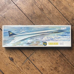 May include: A vintage Airfix Concorde 1:144 scale model kit box. The box features a painted image of the Concorde supersonic jet in flight against a blue sky with clouds. The box has the text "BOAC" and "Concorde 144".