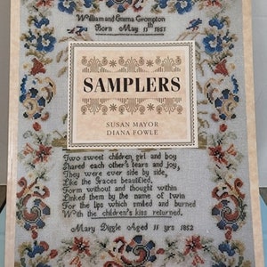 May include: A book cover with a white background and a floral design. The title of the book is "Samplers" and the authors are Susan Mayor and Diana Fowle. The book features 40 full-color plates.