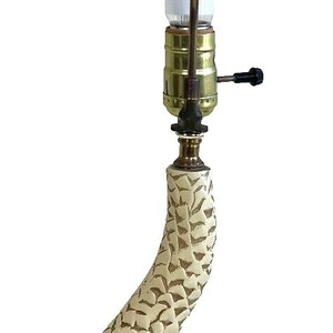 May include: A gold and white table lamp shaped like a fish with a white glass shade. The lamp has a brown wooden base.