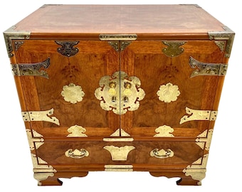May include: A wooden cabinet with two doors and a drawer. The cabinet is decorated with brass hardware and has a dark wood finish.