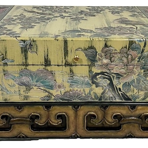May include: A decorative wooden box with a floral design and a gold-colored handle. The box is on a stand with intricate carvings.