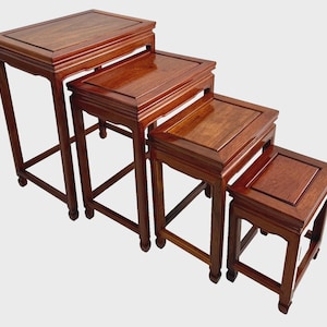 May include: Set of four nesting tables with a rich, reddish-brown finish. Each table has a square top and four straight legs, with a decorative apron. The tables are arranged in a stepped configuration, showcasing their graduated sizes.