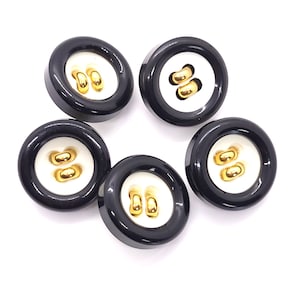 May include: Five black and white buttons with gold-colored accents. The buttons have a glossy black outer ring, a white center, and two gold-colored loops for sewing. The buttons are round and appear to be new.