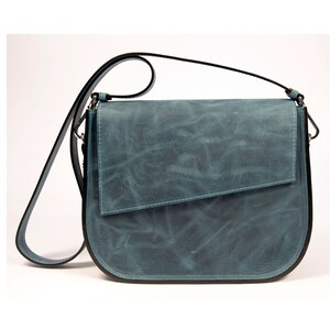 May include: A teal blue leather shoulder bag with a flap closure and a black strap.