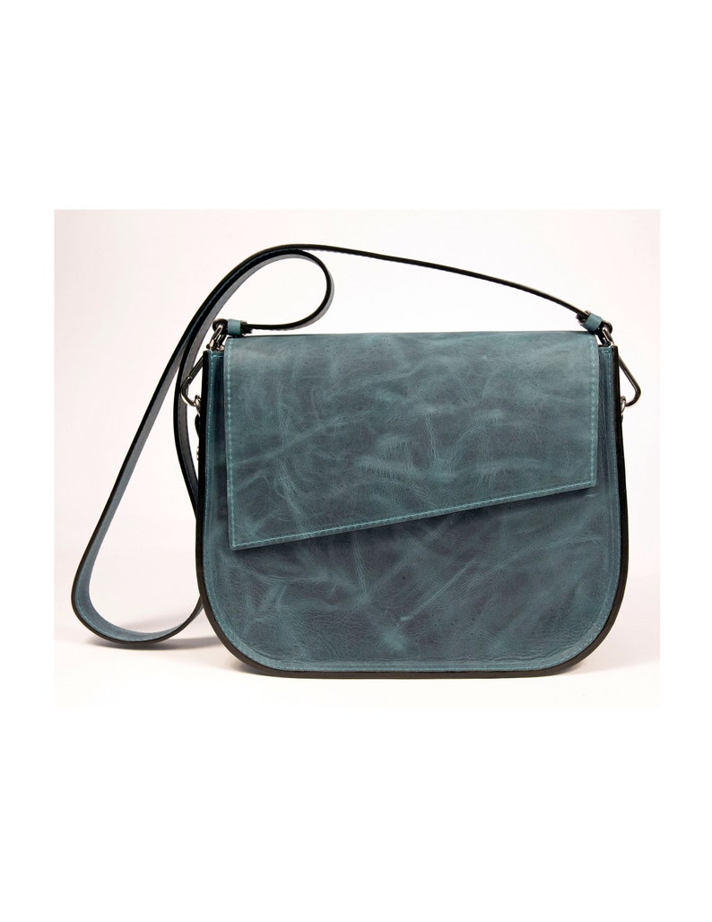 May include: A teal blue leather shoulder bag with a flap closure and a black strap.